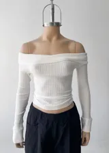 Sweater de punto acanalado color blanco, con escote tipo bardot o descubierto de hombros, de manga larga y corte ajustado al cuerpo.
