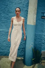 Vestido midi confeccionado en mezcla de lino, con escote redondo, tirantes finos dobles y cierre frontal con botones. Presenta costuras marcadas en el pecho y espalda descubierta con lazada.