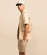 Bermuda masculina color beige claro, con textura, cintura elástica ajustable con cordón y bolsillos laterales.