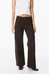 Jean de corte recto y tiro medio, color azul, con detalles de tachas metálicas doradas a lo largo de las costuras laterales externas.