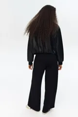 Pantalón negro de tejido liso, corte amplio y tiro alto con cintura elástica.