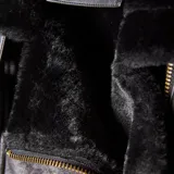 Campera estilo aviador de cuero sintético negro con interior de piel sintética al tono. Presenta cierre frontal cruzado, solapas amplias y detalles de hebillas en el cuello.