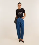 Remera negra de algodón con corte slim, cuello redondo y mangas cortas. Presenta un bloque rectangular frontal con lentejuelas plateadas.