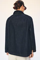 Chaqueta de denim azul oscuro con cuello solapa, manga larga y cierre frontal mediante alamares decorativos de estilo oriental.