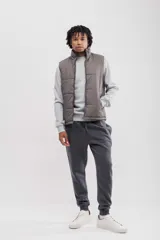 Chaleco puffer color gris topo, con cuello alto y cierre frontal.