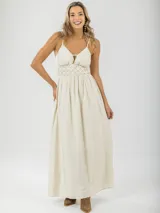 Vestido largo color crema, con breteles finos regulables y guarda trenzada en la cintura.