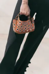 Cartera blanca pequeña con doble asa corta y tachas plateadas.