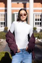 Body blanco de microfibra elastizada, con cuello alto y mangas largas. Cierre inferior con broches corseteros.