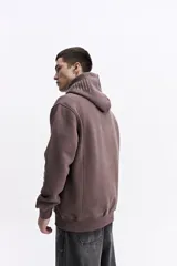 Canguro de felpa color crema, con capucha y bolsillo canguro frontal. Presenta un pequeño estampado con el logo de la marca en el pecho.