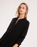 Vestido corto marrón con cuello camisero, abotonado en el frente, mangas largas con elástico en los puños y falda escalonada con volados.