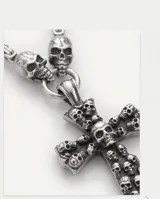 Collar de acero italiano con dije de cruz grande decorado con múltiples calaveras en relieve y dos calaveras adicionales en la unión de la cadena.