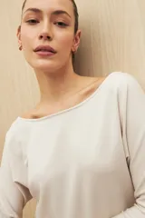 Buzo color beige de calce fluido, con cuello bote y mangas murciélago.