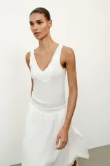 Top de punto canalé en color beige, con escote en pico adornado con una delicada aplicación de encaje blanco y tirantes anchos.