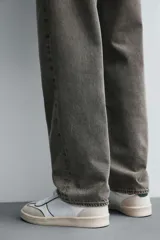 Zapatilla deportiva de estilo retro, color negro, con parte superior fabricada en combinación de piezas de cuero liso y gamuza perforada. Presenta una suela de goma en color marrón oscuro o ahumado en contraste.