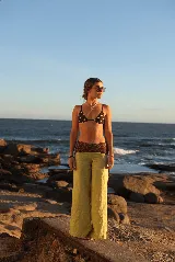 Pantalón de lino de corte ancho y tiro medio, color verde lima. Presenta un caderín y detalles laterales en tela estampada con diseño geométrico en tonos bordó y verde.