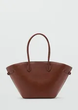 Bolso tipo tote marrón de gran tamaño, con diseño estructurado, dos asas superiores y detalles de hebillas en los laterales. Cuenta con cierre de botón magnético.