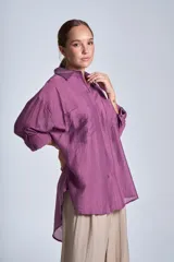 Camisa negra de tela traslúcida con cuello clásico, cierre frontal con botones y dos bolsillos de parche en el pecho.