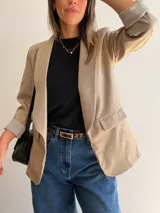 Blazer sastrero de corte clásico con solapas frontales y bolsillos con solapa. Presenta mangas largas con puños vueltos y un diseño forrado que ofrece una caída estructurada y elegante.