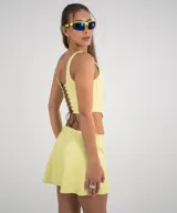 Conjunto amarillo compuesto por un top corto con breteles y espalda con cordones cruzados, y una minifalda acampanada.