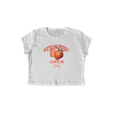 Remera corta blanca de algodón con estampado de dos frutillas y la frase "Strawberry Love is feeling".