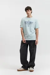 Remera celeste de manga corta con cuello redondo y estampado con la frase "Out of Office All Chasing Dream" en color negro.