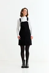 Jumper corto de pana negra con tirantes ajustables, bolsillos frontales y corte recto.