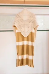 Chal triangular tejido a mano en lana de alpaca natural color crudo, con diseño calado y terminación con borlas.