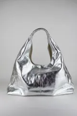 Cartera de cuero vacuno con pelo en diseño animal print similar a piel de ciervo, silueta triangular y asa integrada.
