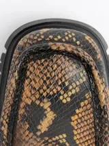 Botín de cuero con estampado de piel de serpiente en tonos ocre y negro, con puntera cuadrada, cierre lateral con cremallera, suela track de goma y tacón cuadrado.