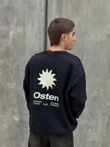 Buzo negro de corte holgado con cuello redondo y puños y bajo acanalados. Estampado frontal con un sol y la palabra "Osten" en blanco.