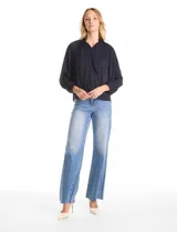 Blusa de gasa con plisado soleil, cuello a la base fruncido con escote en V regulable mediante lazos, y mangas largas abullonadas con puños sastreros.