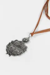 Collar de cordón marrón con dije de escudo plateado con detalles grabados y sol en la parte superior.