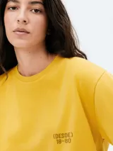 Camiseta de corte oversized color amarillo, con cuello redondo, mangas cortas y estampa pequeña en el pecho con el texto (DESDE) 18-80.