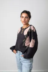 Buzo de punto color negro con estampado floral en tonos rosado y verde. Presenta cuello redondo, mangas largas con diseño abullonado y corte holgado.