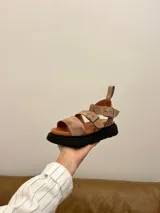 Sandalias de cuero color beige con plataforma de goma negra, tiras anchas con hebillas ajustables y tira trasera con velcro.