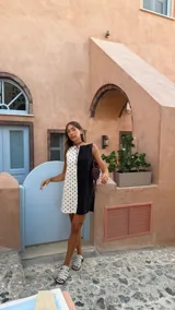 Vestido corto sin mangas con escote recto, confeccionado con paneles combinados: un lado negro liso y el otro blanco con estampado de lunares negros. Posee bolsillos ocultos laterales.