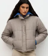 Campera puffer Marfinno con estampa de cuadros mini en tonos beige y negro, de corte recto, cuello alto y cierre frontal con cremallera. Cuenta con mangas largas y forro interior.