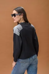 Sweater de punto color negro con cuello redondo y mangas largas, destacando por sus paneles de cuero sintético gris en los hombros.