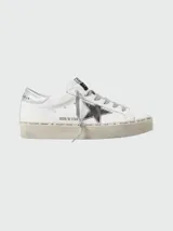 Championes Golden Goose modelo Hi Star, de cuero blanco con estrella plateada y detalles plateados en el talón. Suela alta con inscripciones. Cordones grises.