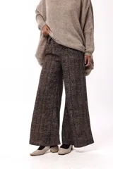 Pantalón de tiro medio-alto con silueta amplia y caída fluida. Presenta un diseño con estampado de espiga en tonos marrones y negros, bolsillos laterales y corte recto.