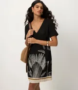 Vestido corto de viscosa y lino color negro con escote en V y mangas cortas. Presenta un estampado de follaje en la parte inferior y detalles de franjas horizontales en el dobladillo.