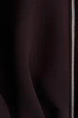 Campera corta de tejido efecto neopreno color marrón oscuro o ciruela, con cuello chimenea alto y cierre frontal metálico. Presenta hombros caídos y un bajo fruncido con elástico que le da un calce holgado.