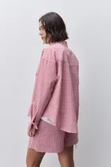 Camisa de calce relajado y silueta amplia con estampado cuadrillé en tonos rojo y blanco. Presenta cuello clásico, cierre frontal mediante botones y mangas largas.