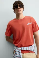 Camiseta de corte relajado con cuello redondo y manga corta. Presenta un estampado frontal con texto en contraste y un acabado con efecto lavado que le otorga una apariencia única.