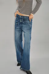 Jean de tiro medio con diseño de doble cintura superpuesta y pierna recta. Confeccionado en denim azul oscuro, presenta cierre y botón metálico, con costuras verticales decorativas en el frente.