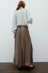 Falda larga de tiro alto, color negro, con diseño fluido y cintura elástica. Cierre lateral con cremallera oculta en costura.