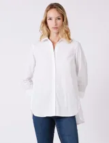 Camisa blanca de algodón con corte clásico y silueta oversize, cuello con solapa y botones ocultos. Mangas tres cuartos con terminación doblada y tajo. Laterales con tajo y botones funcionales. Largo de espalda mayor al largo delantero. Espalda con canesú y pliegue central.