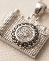 Collar de plata con cadena fina de eslabones y dije colgante en forma de cámara fotográfica decorada con circonias.