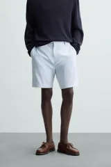Bermuda azul marino de corte regular fit, confeccionada en tejido de algodón y lino. Cuenta con bolsillos frontales y traseros, cierre frontal con cremallera y botón.