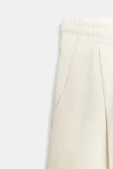 Bermuda de algodón compacto, color crudo, con tiro alto, cintura elástica ajustable con cordones y bolsillos delanteros. Presenta pliegues frontales.